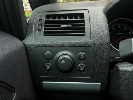 Close-up view of a car dashboard control panel showing various knobs and dials for adjusting air conditioning and lights, captured in a parked vehicle during daylight photo