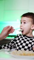 pequeno Garoto tendo jantar com mãe. com fome bebê nutrição. vertical video