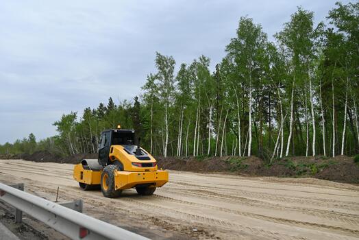 Construction activity on a highway with heavy machinery in a rural area during cloudy weather photo