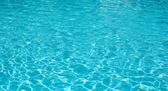 Clear turquoise water shimmering with sunlight, creating intricate patterns on the pool bottom, evoking a sense of summer refreshment and relaxation photo