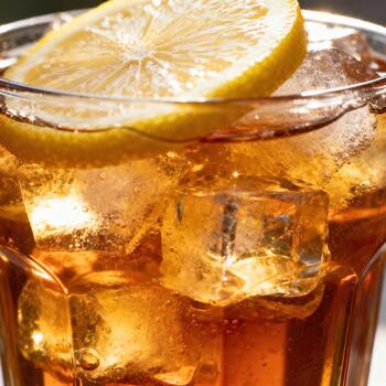 Refreshing iced beverage with a slice of citrus fruit rests in bright sunlight photo
