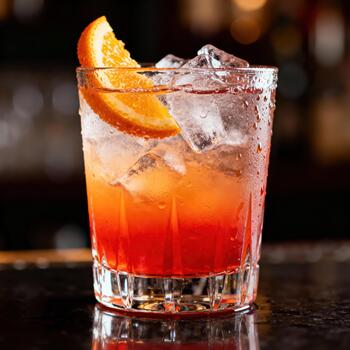 Refreshing chilled beverage with citrus slice sits on dark bar surface photo