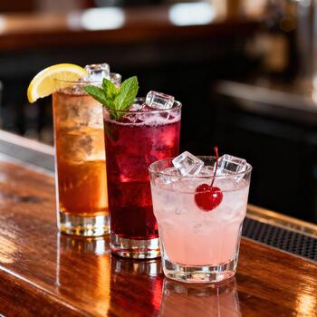 surtido de vistoso con hielo mezclado bebidas presentado en un pulido de madera bar parte superior foto