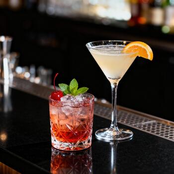 Two colorful mixed drinks sit side by side on a sleek, dark bar counter photo