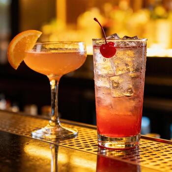 Two colorful chilled mixed drinks rest upon a reflective bar surface with warm background lighting photo