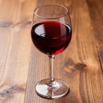 soltero vaso lleno con profundo rojo alcohólico bebida descansa sobre un de madera superficie foto