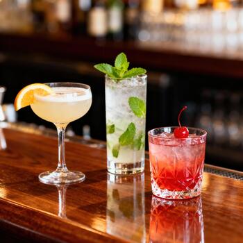 Tres adornado mezclado bebidas descanso sobre un muy pulido de madera bar superficie foto