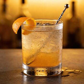 enfriado ámbar cóctel adornado con agrios ánimo se sienta en un mojado superficie en un tenuemente iluminado ajuste foto