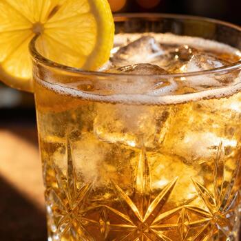 enfriado dorado bebida con hielo cubitos y agrios adornar descansa en un cortar cristal vaso foto