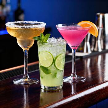 Tres vistoso enfriado bebidas presentando agrios guarnaciones descanso sobre un pulido de madera bar superficie foto