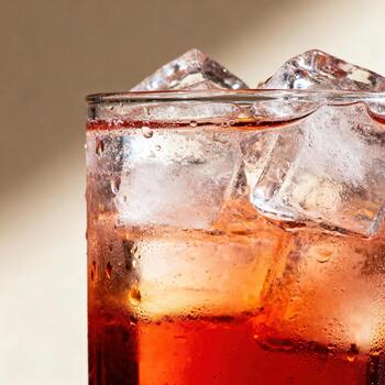 Close up captures refreshing condensation and ice cubes within a vibrant ruby beverage. photo