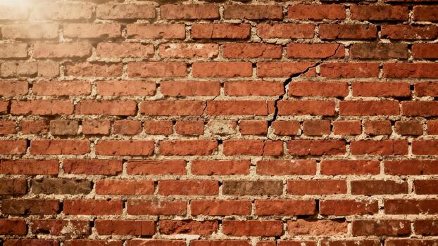 Weathered red brick wall texture displays prominent vertical cracking under soft light photo