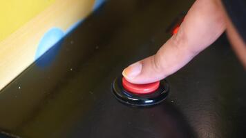 Finger pressing a button on a gaming machine in an arcade video