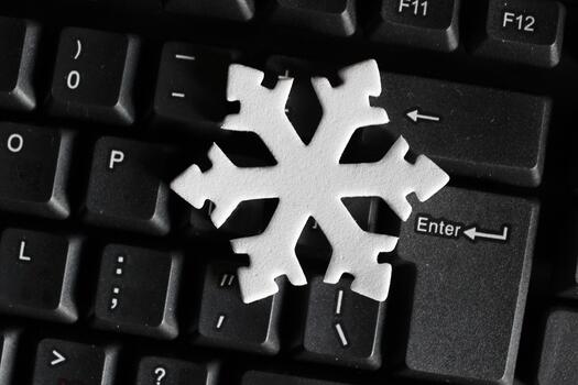 Cold Symbol in a Snowflake Shape on a Dark Pads of Computer Keyboard. Winter Holidays and Office Vacation Concept Photo