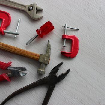 Old but working pliers, a hammer, wire cutters, an adjustable wrench and clamps lie in perfect order on the work table photo