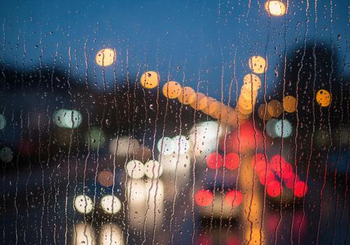 Rainy window view with blurred city lights at dusk creating a beautiful bokeh effect photo