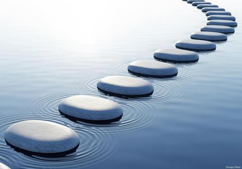 Smooth oval stepping stones creating a peaceful curved path over serene blue water photo