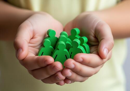 Caring hands cradle a green wooden community of people figures symbolizing unity photo
