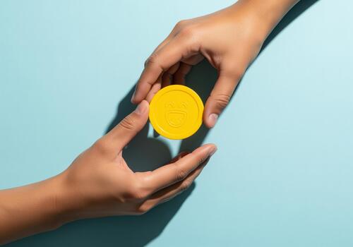 Two hands exchanging a bright yellow happy face token symbolizing joy photo