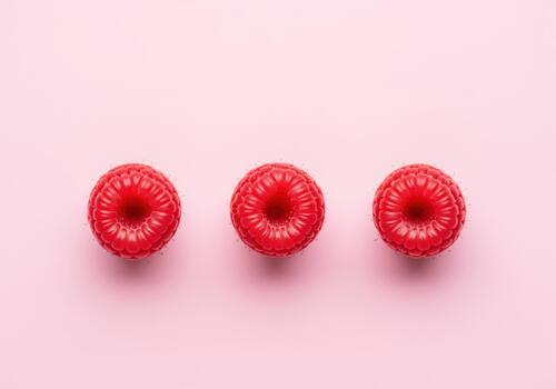 Three vibrant red raspberries perfectly aligned on a clean, minimalist background photo