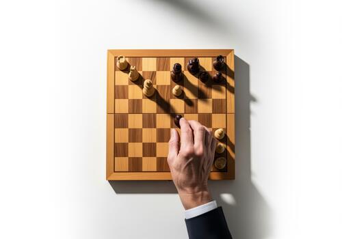 Overhead view of a hand moving a black pawn on a wooden chessboard photo