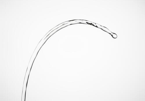 Elegant curved stream of clear water forming a graceful arc with a droplet photo