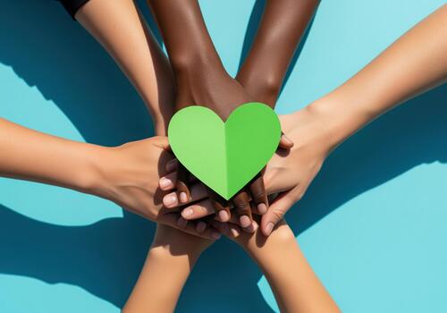 Diverse hands holding green heart symbolizing unity and environmental care photo