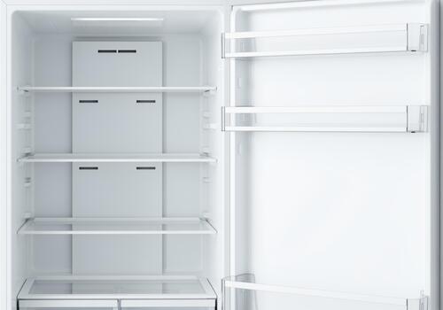 Clean, open, empty refrigerator interior with white shelves and door storage photo