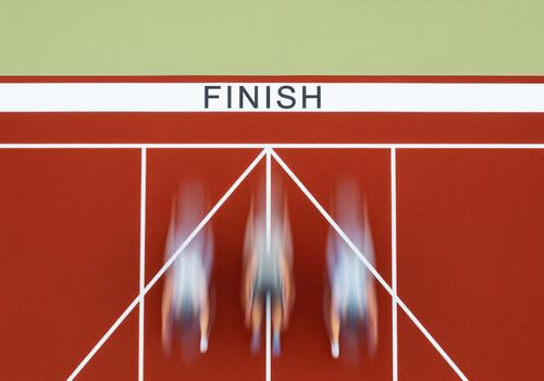 Blurred athletes sprinting across finish line on a red running track photo