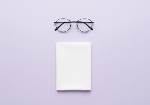 Classic round eyeglasses and a clean white folded tissue on a lavender surface photo