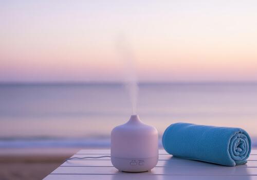 blanco esencial petróleo difusor emitiendo niebla siguiente a un arrollado azul toalla foto