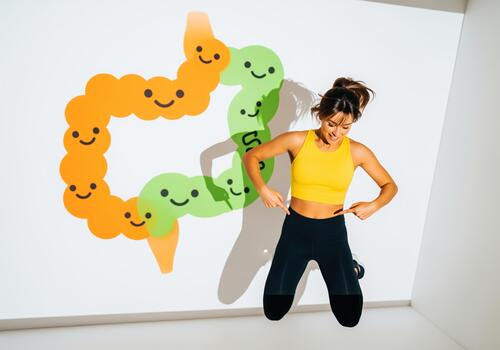 Smiling woman pointing to abdomen with happy cartoon colon projection photo