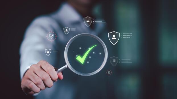 Businessman holding a magnifying glass with digital check mark and security icons, representing workplace safety verification, employee data protection, and secure management systems. photo
