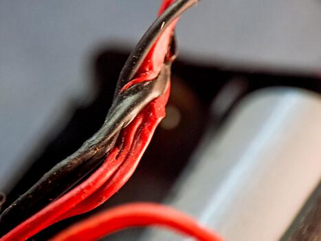 Intertwined red and black wires showcasing connectivity and complexity in a vivid color scheme. photo