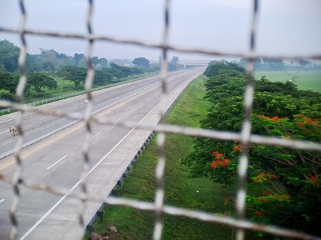 An early morning view of an empty highway through a fence creating leading lines and perspective. photo