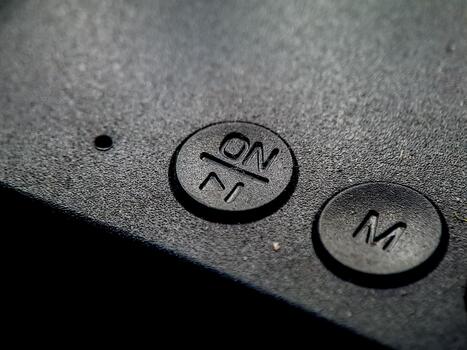 Textured surface showing raised 'On' and 'M' buttons, implying power and mode control setting photo