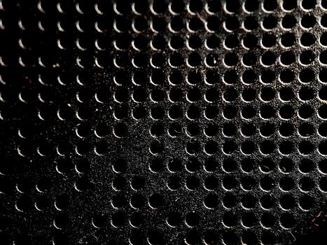 Abstract pattern of dark textured material with evenly spaced perforated holes for visual impact. photo