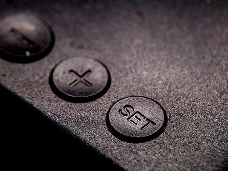 A low angle view of dark grey buttons, one with an 'X' and one with the word 'SET'. photo