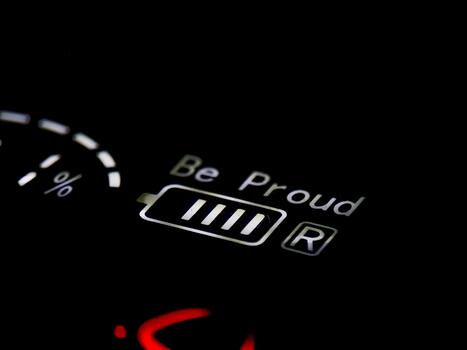 Illuminated display with 'Be Proud' message and a full battery indicator shining in the dark. photo