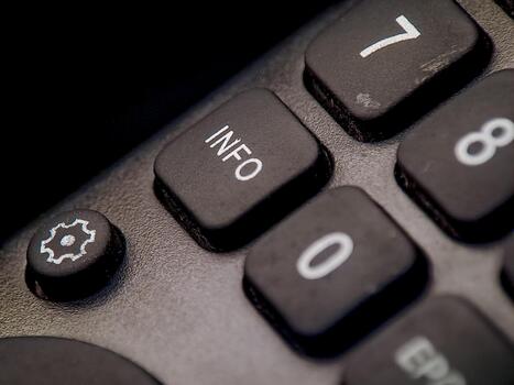 Macro shot depicts the gray remote control featuring number buttons and an information button. photo