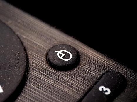 A close up image showing a button with a symbol, part of a remote control device. photo