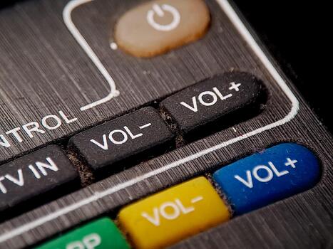 Macro shot of a remote control displaying various volume and control buttons with aged design photo