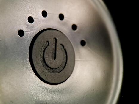 Power button signifies activation with dot array on textured surface contrasting with dark backdrop. photo