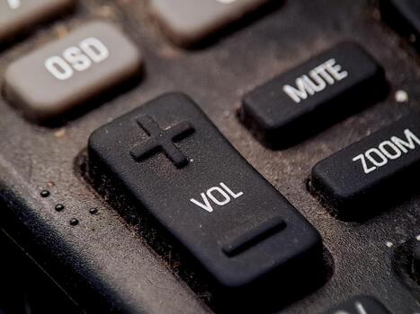 Close up view of a remote control panel showing volume mute and zoom functions clearly visible. photo