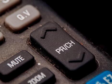 A remote control with channel and function buttons show signs of age and use on the surface. photo