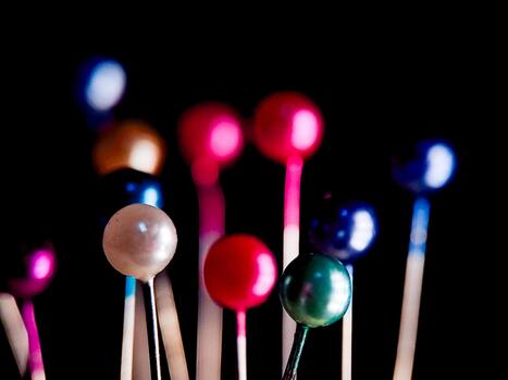 A vibrant array of colorful sphere-topped pins create an abstract, playful composition on black. photo