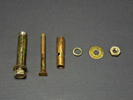 Various loose gold hardware items are neatly arranged on a dark gray textured surface for display. photo