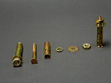 An array of metal fasteners neatly positioned on a dark gray surface displayed in a precise row. photo