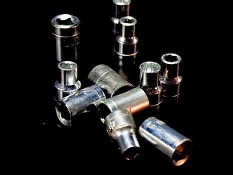 Symmetrical array of assorted metal sockets gleams dramatically on a stark black reflective plane. photo