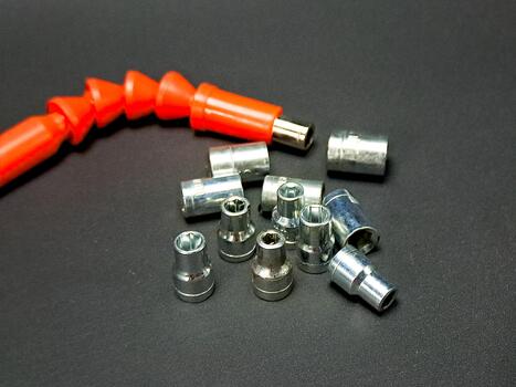 An orange flex extension bar joins a collection of socket adapters on a gray textured surface. photo